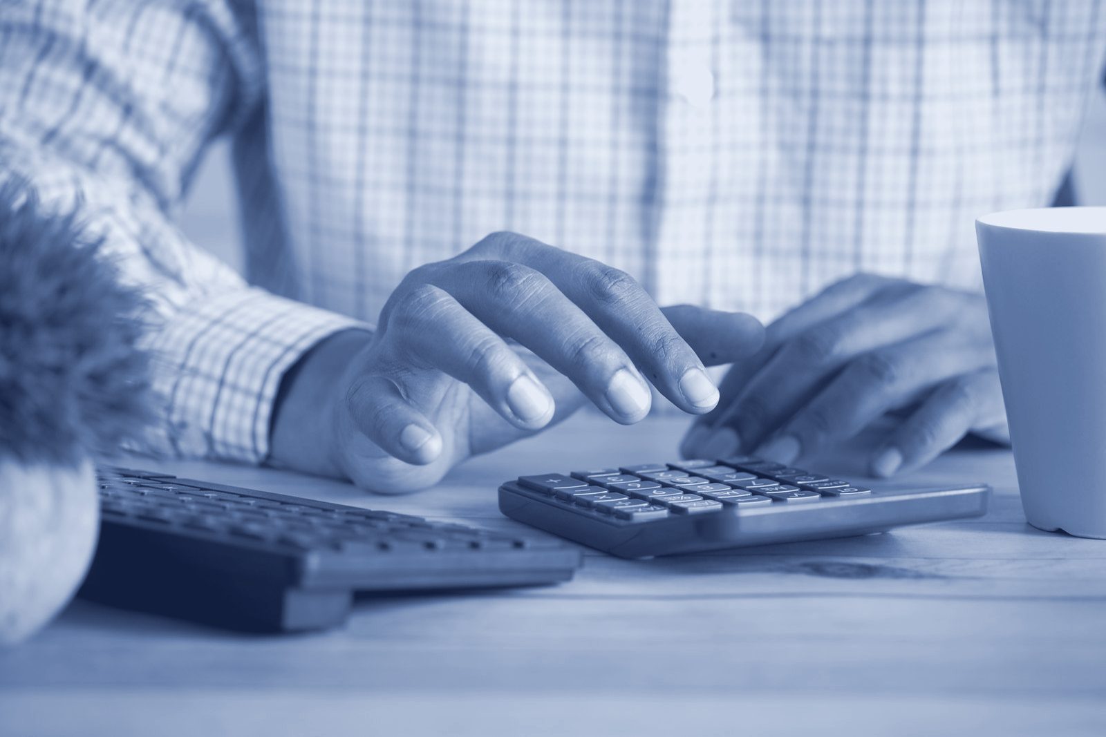 Hands working through costs on a calculator at a desk